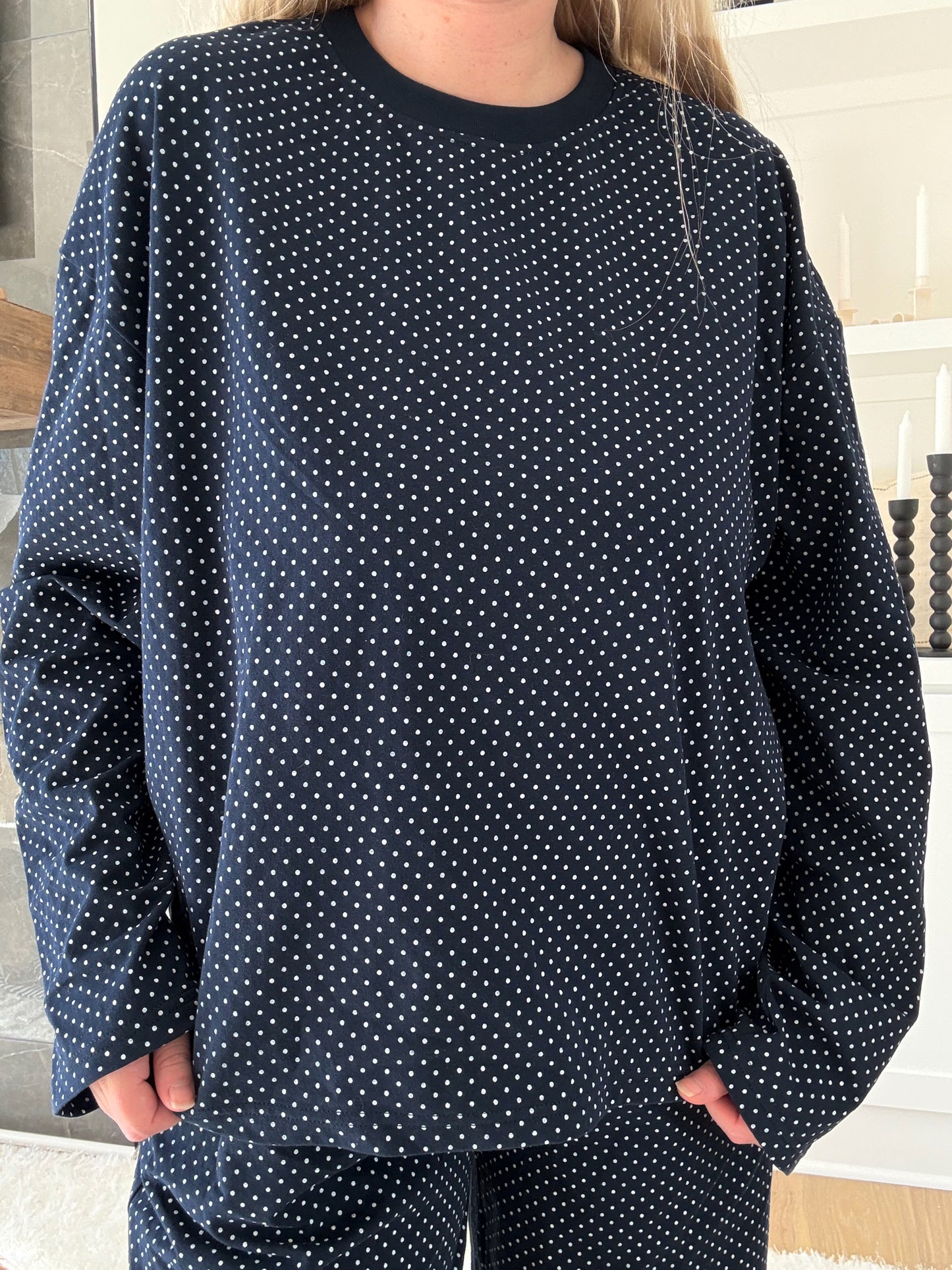 Person wearing a navy blue polka dot pajama set indoors.