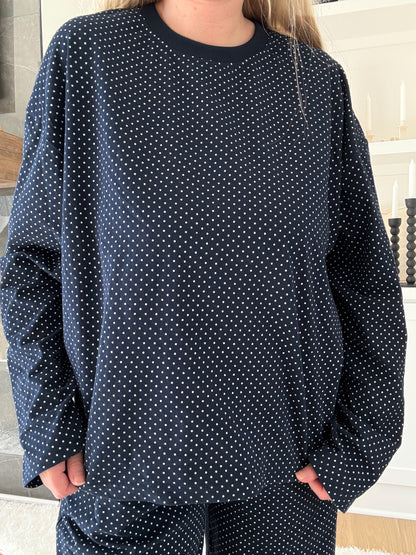 Person wearing a navy blue polka dot pajama set indoors.